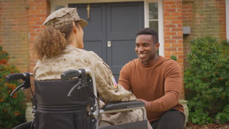 Verletzte-Amerikanische-Soldatin-In-Uniform,-Die-Im-Rollstuhl-Sitzt-Und-Draußen-Mit-Ihrem-Ehemann-Spricht
