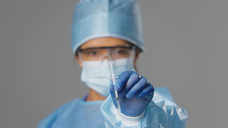 Studio-Shot-Of-Female-Lab-Research-Worker-Wearing-PPE-And-Glasses-Holding-Syringe-For-Vaccination
