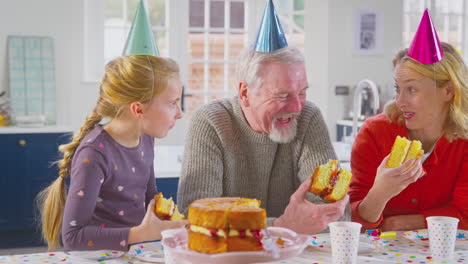 Abuelos-Con-Nieta-Celebrando-Cumpleaños-Comiendo-Pastel-Juntos-En-Casa