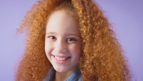 Studio-Portrait-Of-Smiling-Girl-With-Red-Hair-Against-Purple-Background