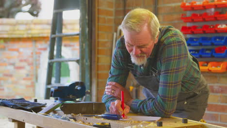 Senior-Male-Carpenter-In-Garage-Workshop-Sketching-Out-Design-On-Paper