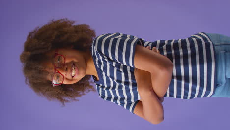 Vertical-Video-Of-Smiling-Boy-Wearing-Red-Glasses-Against-Purple-Background