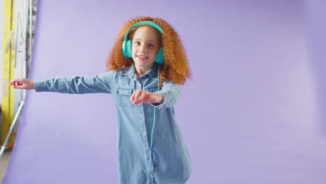 Studio-Shot-Of-Girl-Wearing-Headphones-And-Dancing-Against-Purple-Background