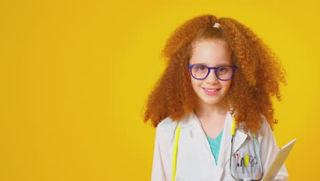Studioporträt-Eines-Als-Arzt-Oder-Chirurg-Verkleideten-Mädchens-Mit-Digitalem-Tablet-Vor-Gelbem-Hintergrund