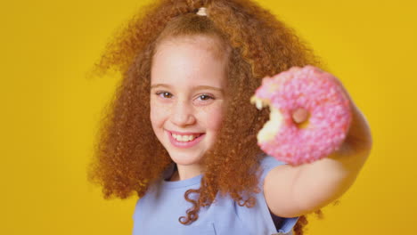Studioporträt-Eines-Mädchens,-Das-Donut-Vor-Gelbem-Hintergrund-Isst