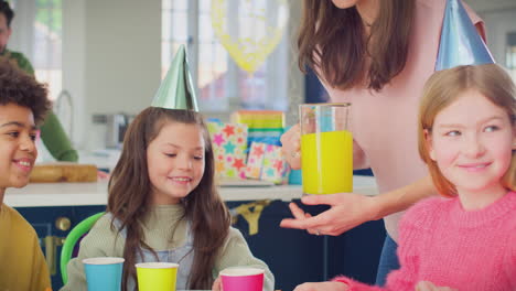 Mutter-Gießt-Saft-In-Tassen,-Während-Kinder-Zu-Hause-Geburtstagsfeier-Genießen