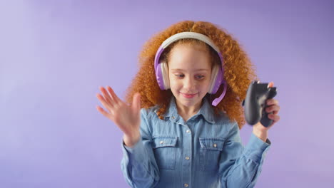 Studioaufnahme-Eines-Mädchens,-Das-Ein-Gaming-Headset-Mit-Controller-Vor-Violettem-Hintergrund-Trägt