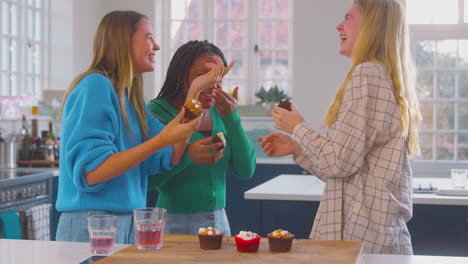 Gruppe-Von-Mädchen-Im-Teenageralter,-Die-Zu-Hause-In-Der-Küche-Cupcakes-Essen-Und-Spaß-Haben