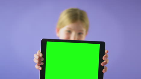 Retrato-De-Estudio-De-Una-Niña-Usando-Una-Tableta-Digital-Con-Pantalla-Verde-Sobre-Fondo-Púrpura