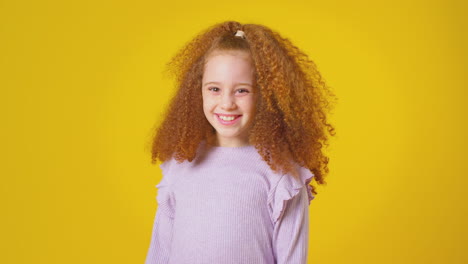 Studio-Portrait-Of-Smiling-Girl-With-Red-Hair-Against-Yellow-Background
