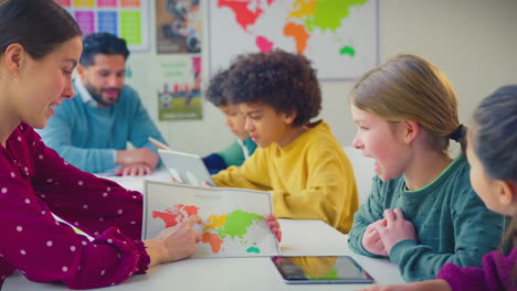 Grundschüler-Mit-Digitalem-Tablet-Betrachten-Karte-Im-Geographieunterricht-Im-Klassenzimmer