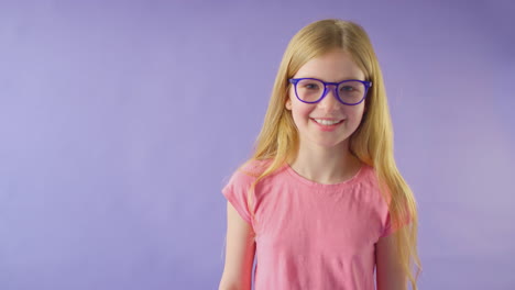 Studioaufnahme-Eines-Lächelnden-Mädchens-Mit-Langen-Haaren-Und-Blauer-Brille-Vor-Violettem-Hintergrund