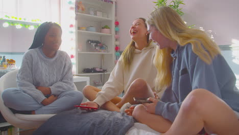 Group-Of-Multi-Cultural-Teenage-Girl-Friends-With-Mobile-Phones-Hanging-Out-In-Bedroom-At-Home