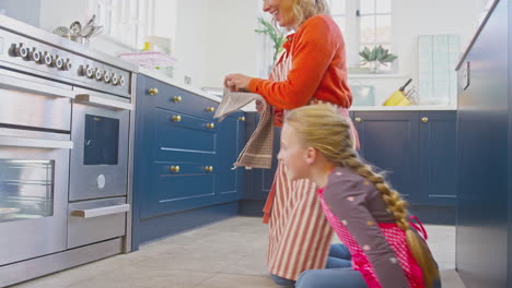 Grandmother-And-Granddaughter-Take-Freshly-Baked-Cupcakes-Out-Of-The-Oven-In-Kitchen-At-Home