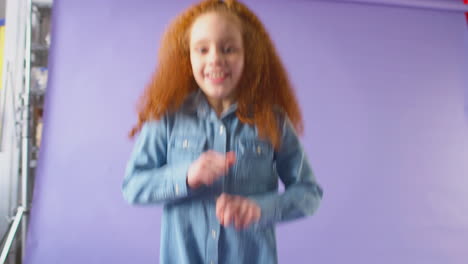 Studioporträt-Eines-Mädchens-Mit-Roten-Haaren,-Das-Vor-Violettem-Hintergrund-Tanzt