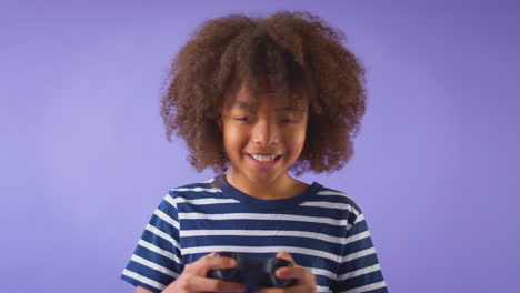 Studio-Shot-Of-Boy-Gaming-With-Controller-Against-Purple-Background