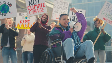 Female-Protestor-In-Wheelchair-With-Placard-And-Megaphone-On-Demonstration-Against-Climate-Change