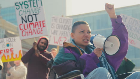 Female-Protestor-In-Wheelchair-With-Placard-And-Megaphone-On-Demonstration-Against-Climate-Change