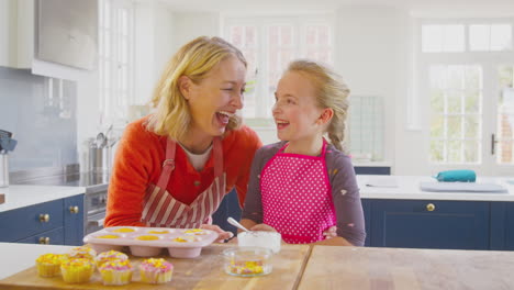 Portrait-Of-Grandmother-With-Granddaughter-Having-Fun-Decorating-Homemade-Cakes-On-Kitchen-Counter