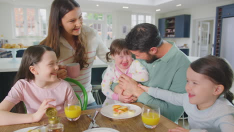 Family-With-Down-Syndrome-Daughter-Sitting-Around-Table-At-Home-Eating-Breakfast