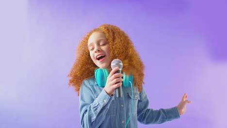 Studioaufnahme-Eines-Mädchens-Mit-Kopfhörern,-Das-Vor-Violettem-Hintergrund-Karaoke-Ins-Mikrofon-Singt