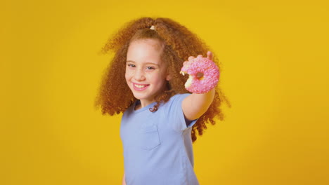 Studioporträt-Eines-Mädchens,-Das-Donut-Vor-Gelbem-Hintergrund-Isst