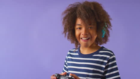 Studio-Shot-Of-Boy-Gaming-With-Controller-Against-Purple-Background