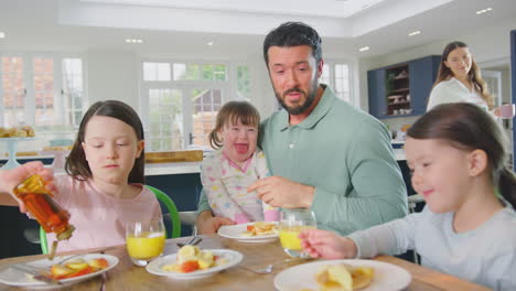 Familie-Mit-Down-Syndrom-Tochter-Sitzt-Zu-Hause-Am-Tisch-Und-Frühstückt