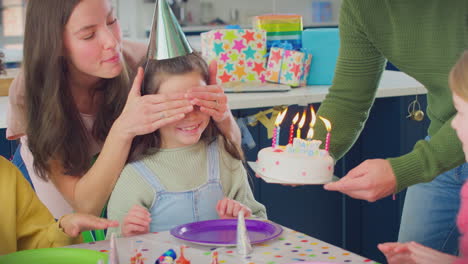 Mädchen-Bläst-Kerzen-Auf-Geburtstagstorte-Auf-Einer-Party-Mit-Eltern-Und-Freunden-Zu-Hause-Aus