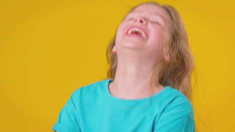 Studioporträt-Eines-Mädchens-Mit-Langen-Haaren,-Das-Vor-Gelbem-Hintergrund-Lacht