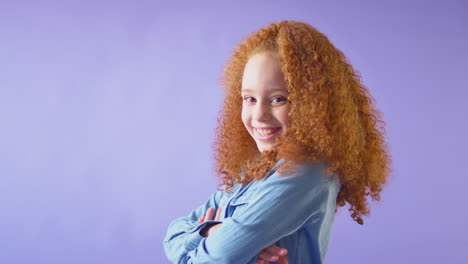 Studio-Portrait-Of-Smiling-Girl-With-Red-Hair-Against-Purple-Background