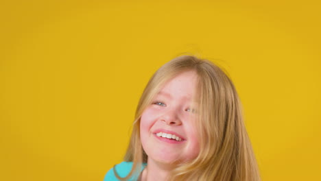 Studioporträt-Eines-Mädchens-Mit-Langen-Haaren,-Das-Vor-Gelbem-Hintergrund-Lacht-Und-Sich-Dreht