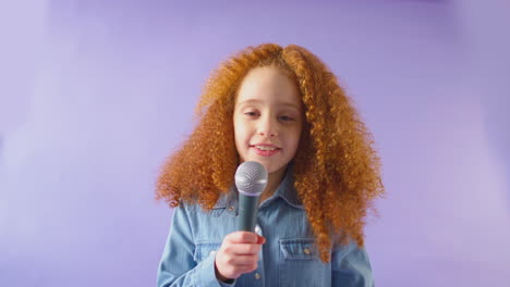 Studioaufnahme-Eines-Mädchens,-Das-Vor-Violettem-Hintergrund-Karaoke-Ins-Mikrofon-Singt