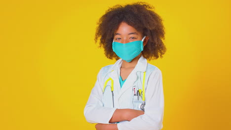 Studio-Portrait-Of-Boy-Dressed-As-Doctor-Or-Surgeon-Wearing-Face-Mask-Against-Yellow-Background