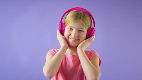 Studioporträt-Eines-Mädchens-Mit-Kabellosen-Kopfhörern,-Das-Musik-Vor-Gelbem-Hintergrund-Streamt