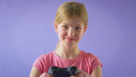 Studioaufnahme-Eines-Mädchens,-Das-Mit-Einem-Controller-Vor-Violettem-Hintergrund-Spielt