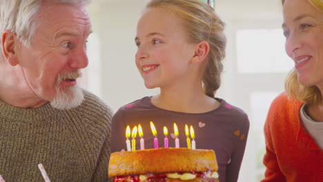 Großeltern-Und-Enkelin-Feiern-Gemeinsam-Das-Ausblasen-Von-Kerzen-Auf-Der-Geburtstagstorte-Zu-Hause