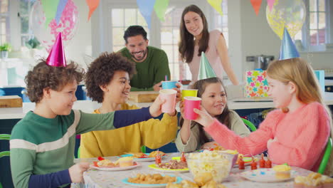 Kind-Mit-Eltern-Und-Freunden-Zu-Hause-Stößt-Mit-Tassen-An,-Um-Den-Geburtstag-Zu-Feiern
