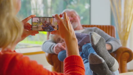 Grandmother-Taking-Picture-Of-Grandfather-And-Granddaughter-Having-Daytime-Sleep-At-Home-Together