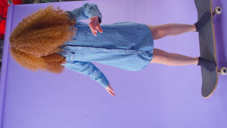 Vertikales-Video-Eines-Jungen-Mädchens,-Das-Auf-Einem-Skateboard-Vor-Violettem-Hintergrund-Reitet