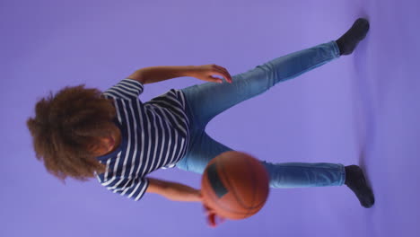 Vídeo-Vertical-De-Un-Niño-Regateando-Con-Baloncesto-Sobre-Fondo-Morado