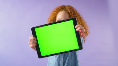Retrato-De-Estudio-De-Una-Niña-Usando-Una-Tableta-Digital-Con-Pantalla-Verde-Sobre-Fondo-Púrpura