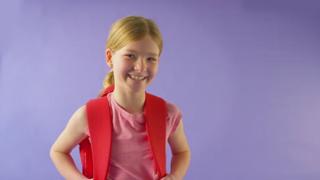 Studio-Shot-Of-Girl-With-Backpack-Going-To-School-On-Purple-Background