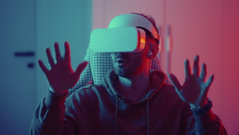 Cyber-gamer-in-VR-glasses-plays-virtual-reality-game-in-neon-futuristic-space.-Gaming-concept.-Young-handsome-man-looks-around-and-shooting-from-virtual-blaster-gun.-High-quality-4k-footage