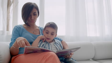 Happy-mother-and-child-son-reading-book-laughing-in-bed.-Happy-family-mother-and-child-son-reading-holding-book-lying-in-bed-smiling-mom-baby-sitter