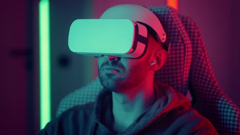 Cyber-gamer-in-VR-glasses-plays-virtual-reality-game-in-neon-futuristic-space.-Gaming-concept.-Young-handsome-man-looks-around-and-shooting-from-virtual-blaster-gun.-High-quality-4k-footage