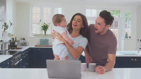 Loving-Transgender-Family-With-Baby-At-Home-Together-With-Laptop-Drinking-Coffee-At-Kitchen-Counter