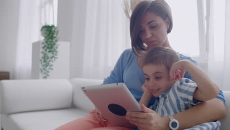 Mother-and-son-sitting-on-sofa-using-digital-tablet.-Happy-mom-and-little-boy-using-tablet-with-touchscreen-together-watching-a-video.-Smiling-mother-and-cute-boy-playing-on-digital-tablet.
