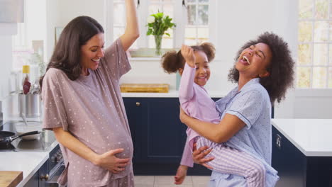 Familia-Embarazada-Con-Dos-Mamás-Bailando-Haciendo-Panqueques-Matutinos-En-La-Cocina-Con-Su-Hija