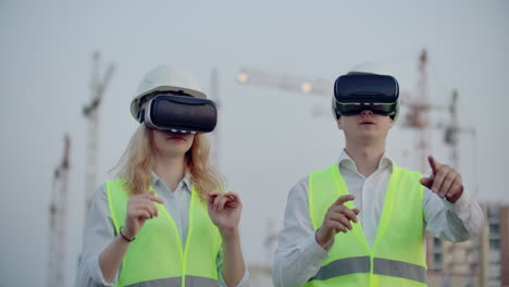 Two-inspectors-of-the-future-on-the-construction-site-use-virtual-reality-glasses-on-the-background-of-buildings-and-cranes